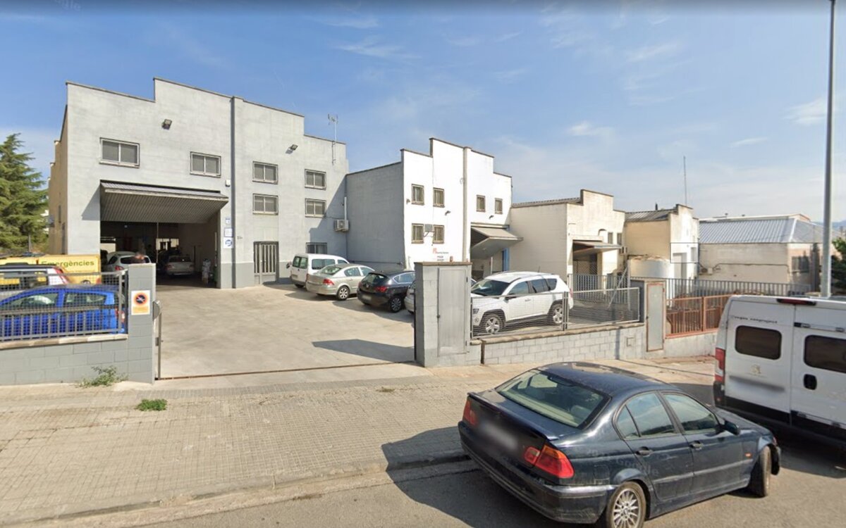 Fachada del taller Automoción CTS en Sentmenat, con persiana abierta y vehículos en el parking